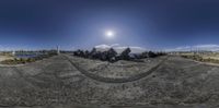 the beach has rock sculptures that appear to be holding something out in the wind in a 360 - lens photo