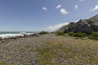 rocky beach with a path to the ocean in the background and blue skies above and below