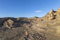 a rocky cliff near the ocean with some waves on it, and blue skies above