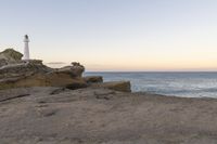 a view of the sea with a lighthouse on a cliff overlooking the ocean and a person taking a photograph