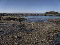 a rocky area along the shore next to a body of water with rocks and gravel in it