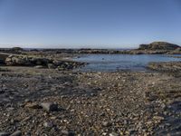 a rocky area along the shore next to a body of water with rocks and gravel in it