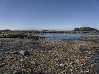 a rocky area along the shore next to a body of water with rocks and gravel in it