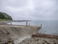 the shore line is made up of a rocky and concrete wall and sand by the ocean