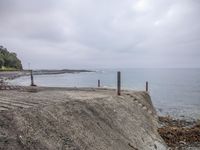 the shore line is made up of a rocky and concrete wall and sand by the ocean