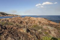 a view of the ocean from a rocky shoreline next to a beach with some rocks