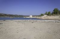 an area of rocky ground with some trees near the water, and a body of water in the middle