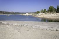 an area of rocky ground with some trees near the water, and a body of water in the middle