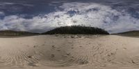 a photograph of a sand and trees area under a cloudy sky and clouds above it