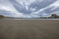 a cloudy sky over a beach covered in sand and hills under a cloudy blue sky