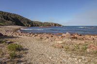 rocks and gravel on a rocky beach with blue skies above them and a blue sky in the distance