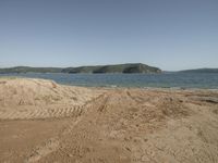 a brown sandy beach with a lot of dirt around it and hills in the distance