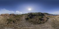 the sunny sun shines over the hillside by the water and sand shore near an ocean