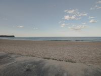 a man rides a skateboard on the beach in front of the water and the ocean