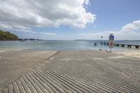 an empty beach with a pier in the middle of it and several boats near by