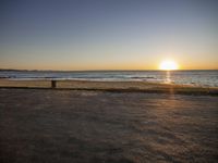 a bench is by the ocean during the sunset on the beach at sunset cove in newport, rhode