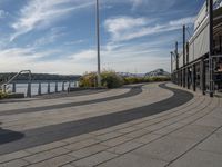 a walkway that leads to two rivers, a large bridge, and a building on a hill