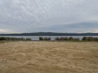 a wide area near the water has dirt in it and a few patches of grass that look like mounds