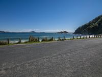 a large body of water near a dirt road and hill on the edge of the ocean