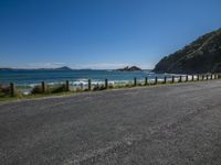 a large body of water near a dirt road and hill on the edge of the ocean