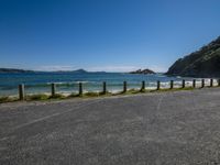 a large body of water near a dirt road and hill on the edge of the ocean