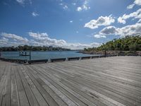 a man walking across a wooden dock next to a body of water with boats in it