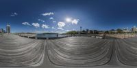 a fish eye lens on an empty concrete area next to the water and clouds above it