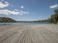 wood decking on the edge of a body of water with blue sky and clouds