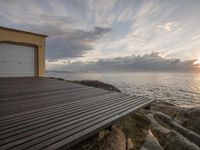 a wooden dock extends to the ocean on a sunny day with a sunrise over the water