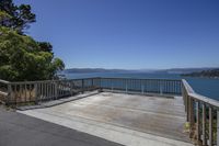 an empty wooden patio with blue sky in the background and a view of lake with mountains