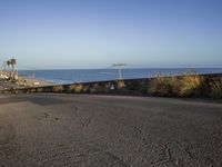 a stop sign and a beach at sunrise as seen from a hill top near the ocean