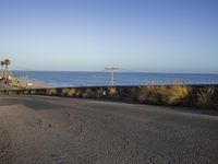 a stop sign and a beach at sunrise as seen from a hill top near the ocean