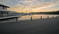 a boat dock next to a body of water and some docks at sunset with several boats