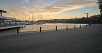 a bridge over water and sailboats docked on a dock at sunrise time and the sky is