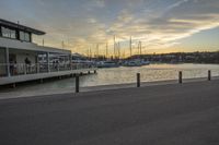 a view of a marina with boats on the water at sunset in the background and people sitting around