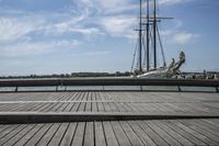 a long wooden dock with a ship docked on it and a bench by the water