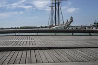 a long wooden dock with a ship docked on it and a bench by the water