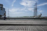 a long wooden dock with a ship docked on it and a bench by the water