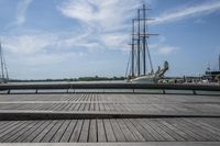 a long wooden dock with a ship docked on it and a bench by the water