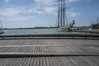 a long wooden dock with a ship docked on it and a bench by the water