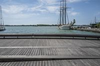 a long wooden dock with a ship docked on it and a bench by the water