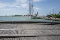 a long wooden dock with a ship docked on it and a bench by the water
