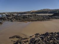 an empty sandy beach with waves and rocks at the shore line in the foreground