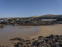 an empty sandy beach with waves and rocks at the shore line in the foreground