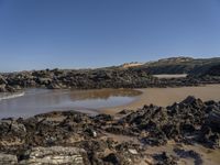 an empty sandy beach with waves and rocks at the shore line in the foreground