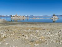 an empty beach is shown next to the water and snow - capped mountains on a sunny day