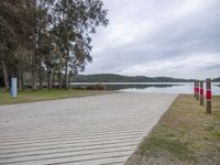 a park with a picnic table, benches, and trees at the edge of a lake