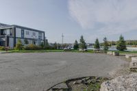 a park near the water with rocks on the road and houses on the other side