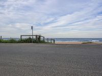 two benches sitting next to each other on a road near the beach near a body of water