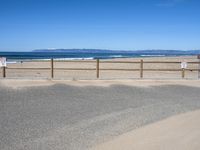 a paved beach with a fence in front of it and the ocean in the distance